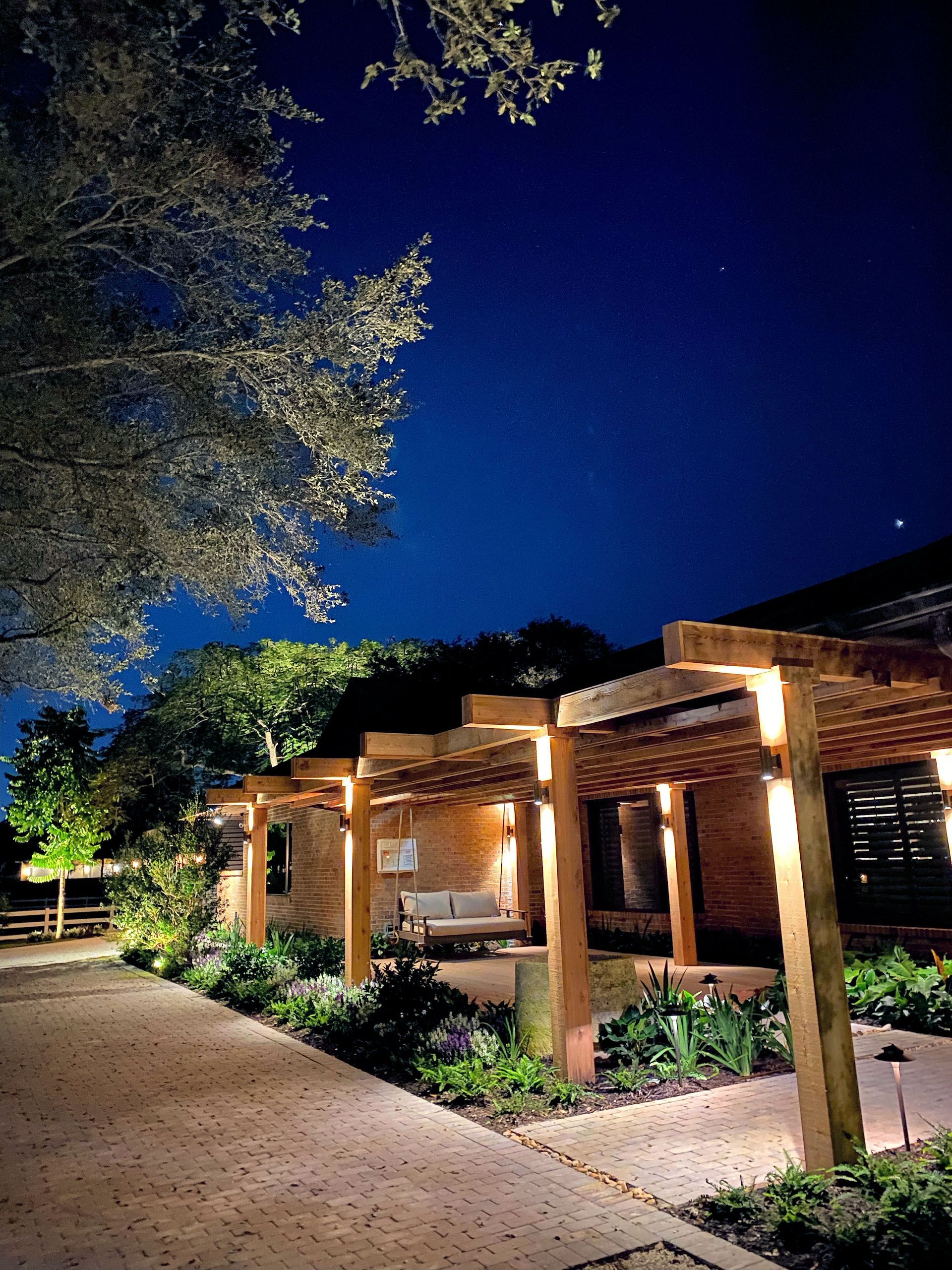 Lit walkway beside a warmly lit pavilion under a deep blue evening sky