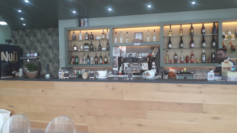 Un bar con un bancone di legno e scaffali pieni di bottiglie di alcolici.