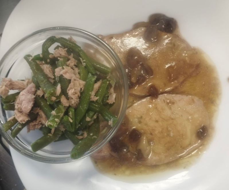 Un piatto di cibo con fagiolini e carne sopra