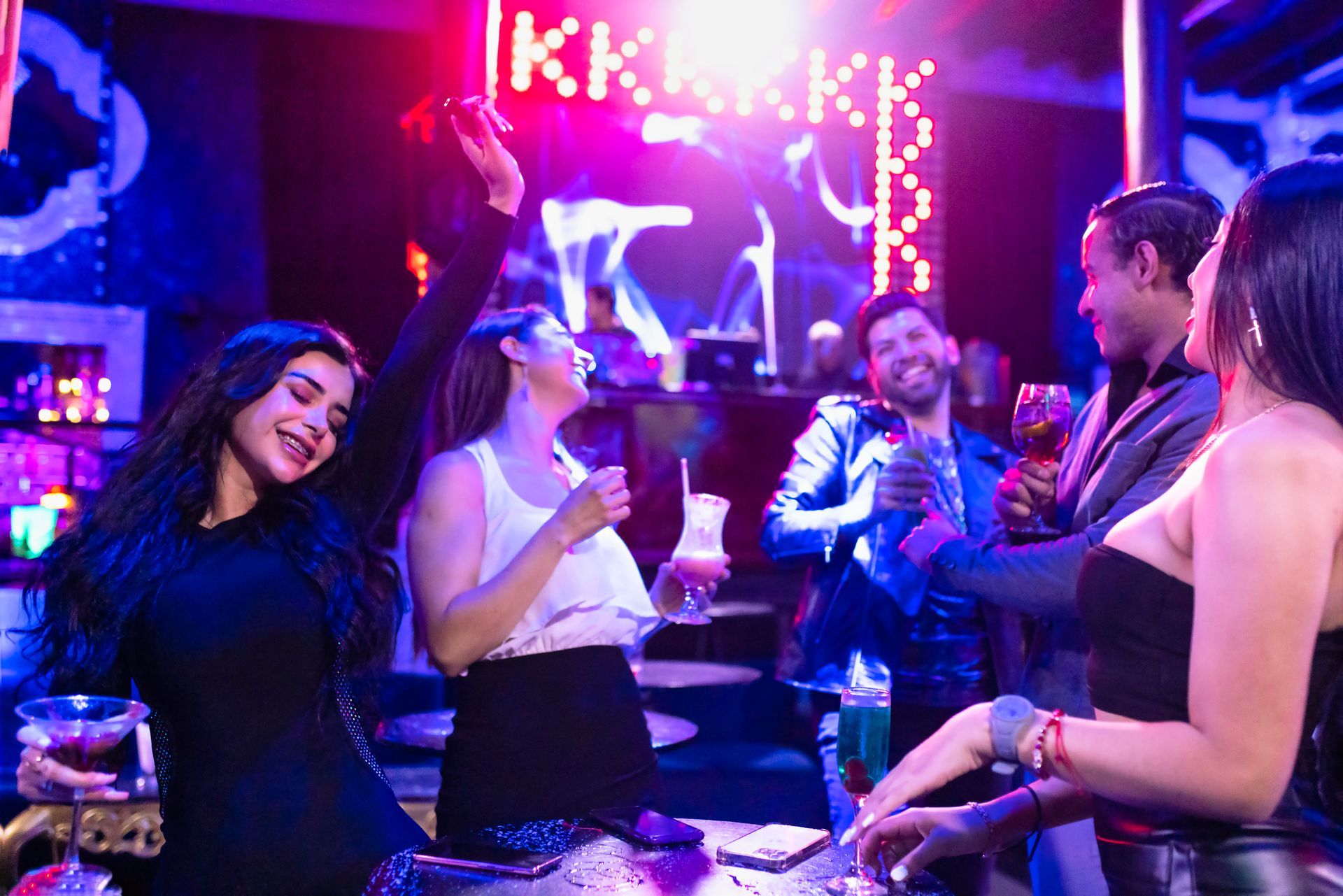 Un gruppo di persone balla in una discoteca tenendo in mano dei drink.