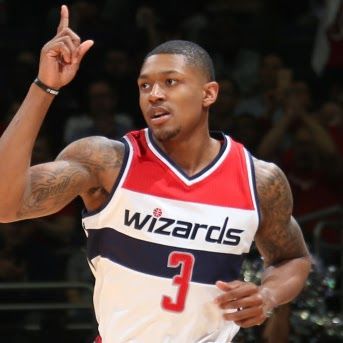 Basketball player in Wizards jersey pointing up.