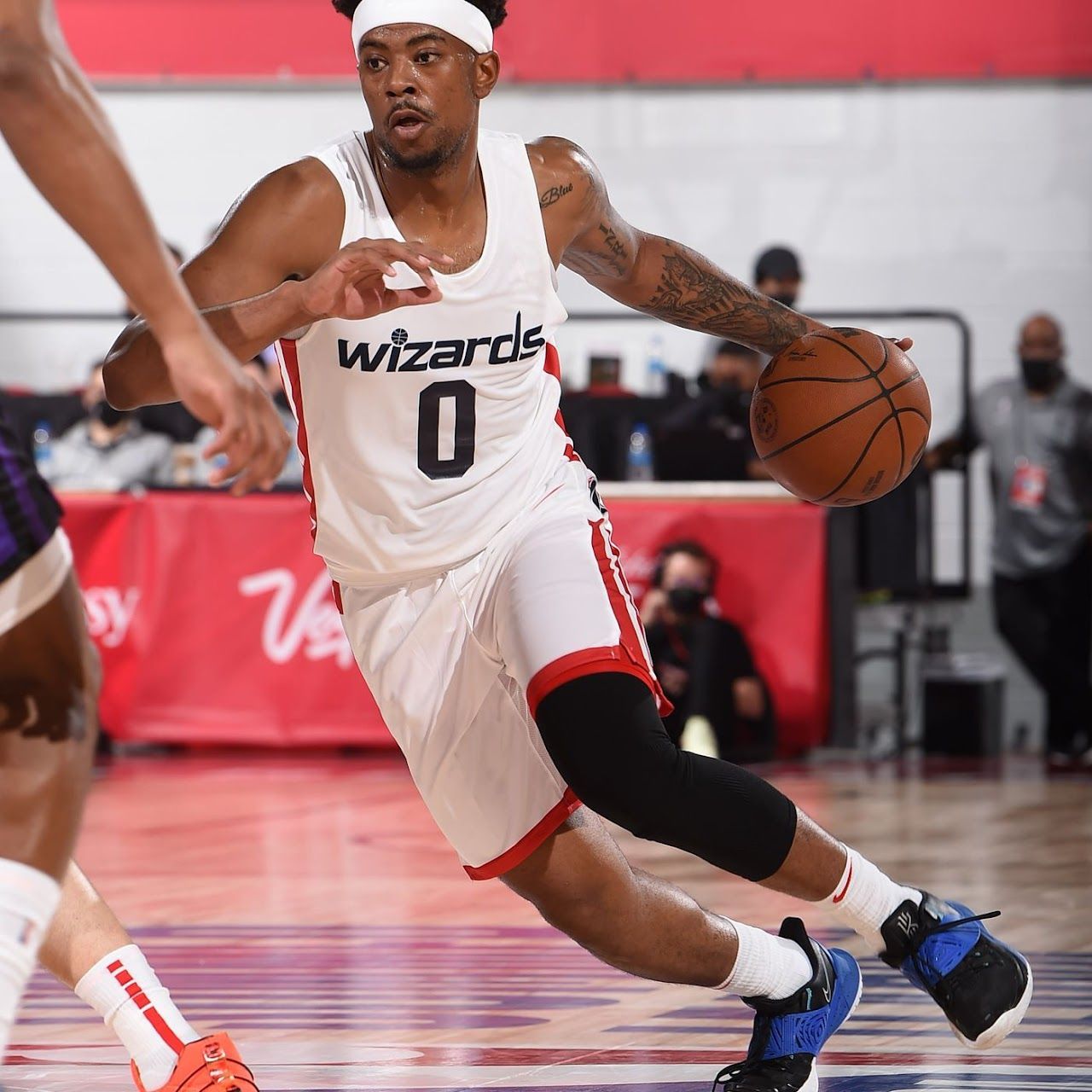 Basketball player in white Wizards jersey dribbling ball on court.