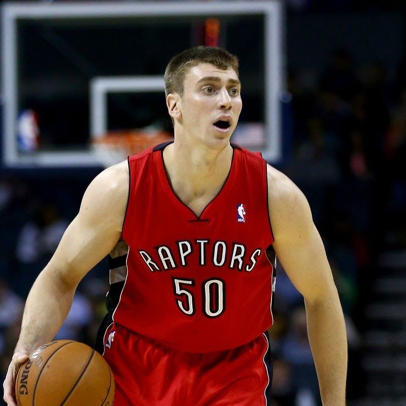 Basketball player in red Raptors jersey, dribbling ball on court.