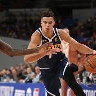 Basketball player dribbling a ball on a court; wearing a blue and yellow jersey.