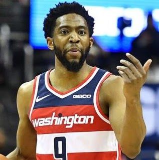 Basketball player in Washington Wizards jersey gesturing with his hand.