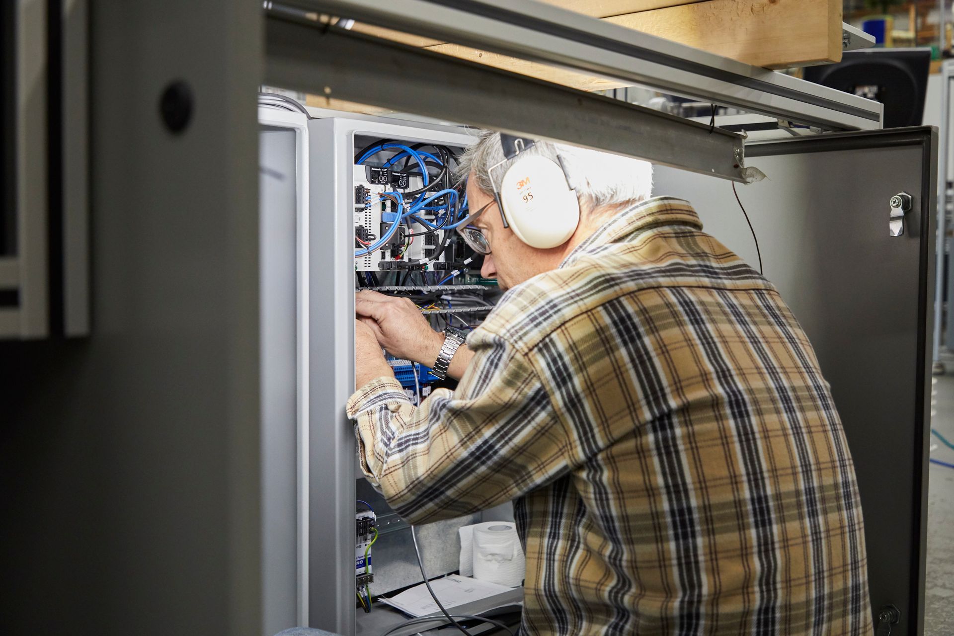 A man wearing headphones is working on a machine in a factory. rothgreaves 