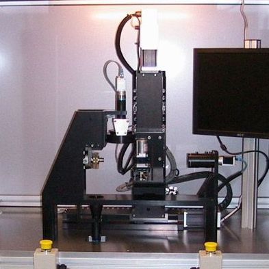 A machine is sitting on a table next to a monitor rothgreaves custom manufacturing