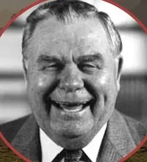 A man in a suit and tie is smiling in a black and white photo.