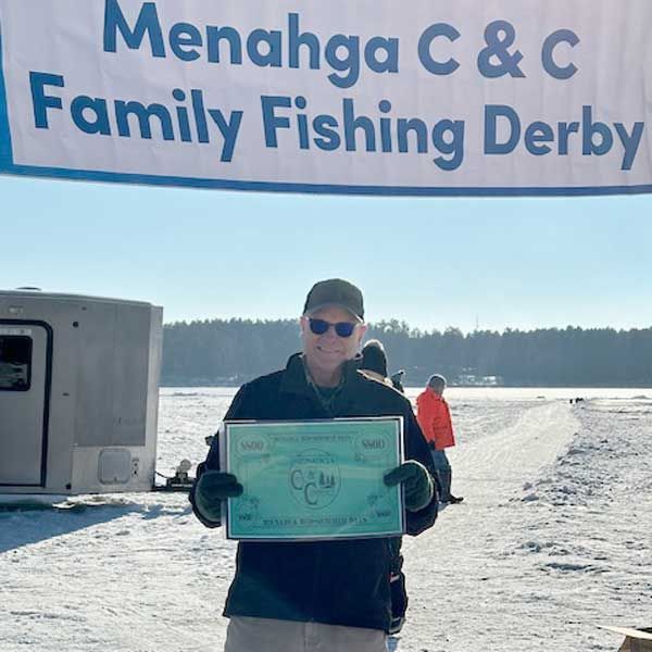 A person holding a certificate at the Menahga C & C Family Fishing Derby on a frozen, snow-covered lake.