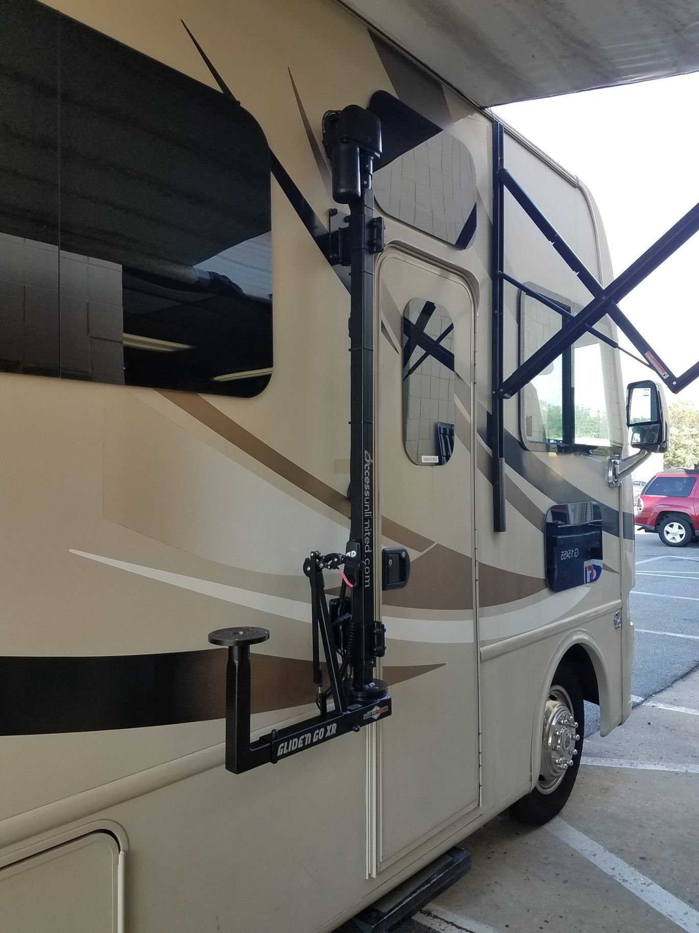 A rv with a bike rack attached to it is parked in a parking lot.