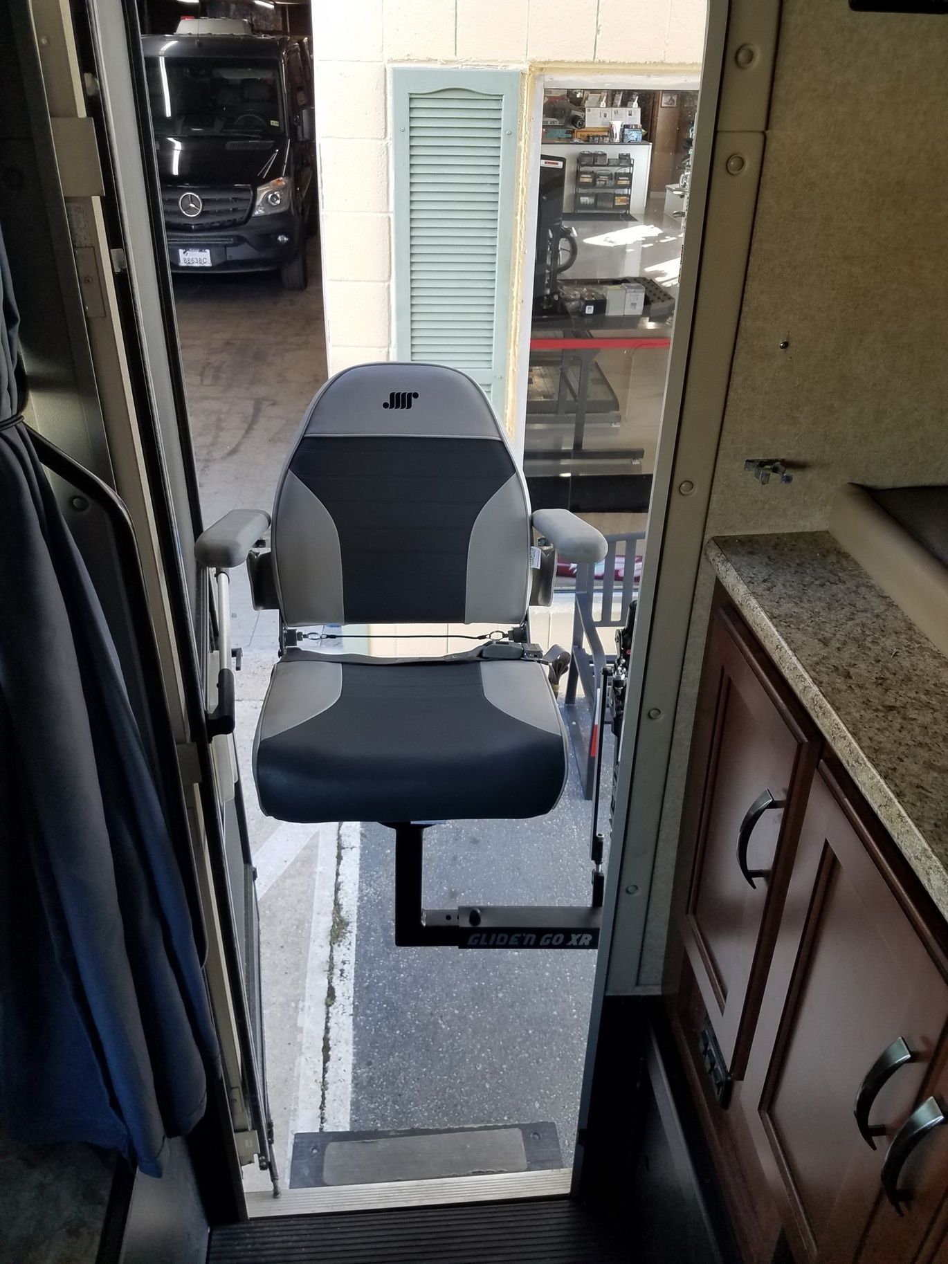 A black and gray chair is sitting in the doorway of a vehicle.