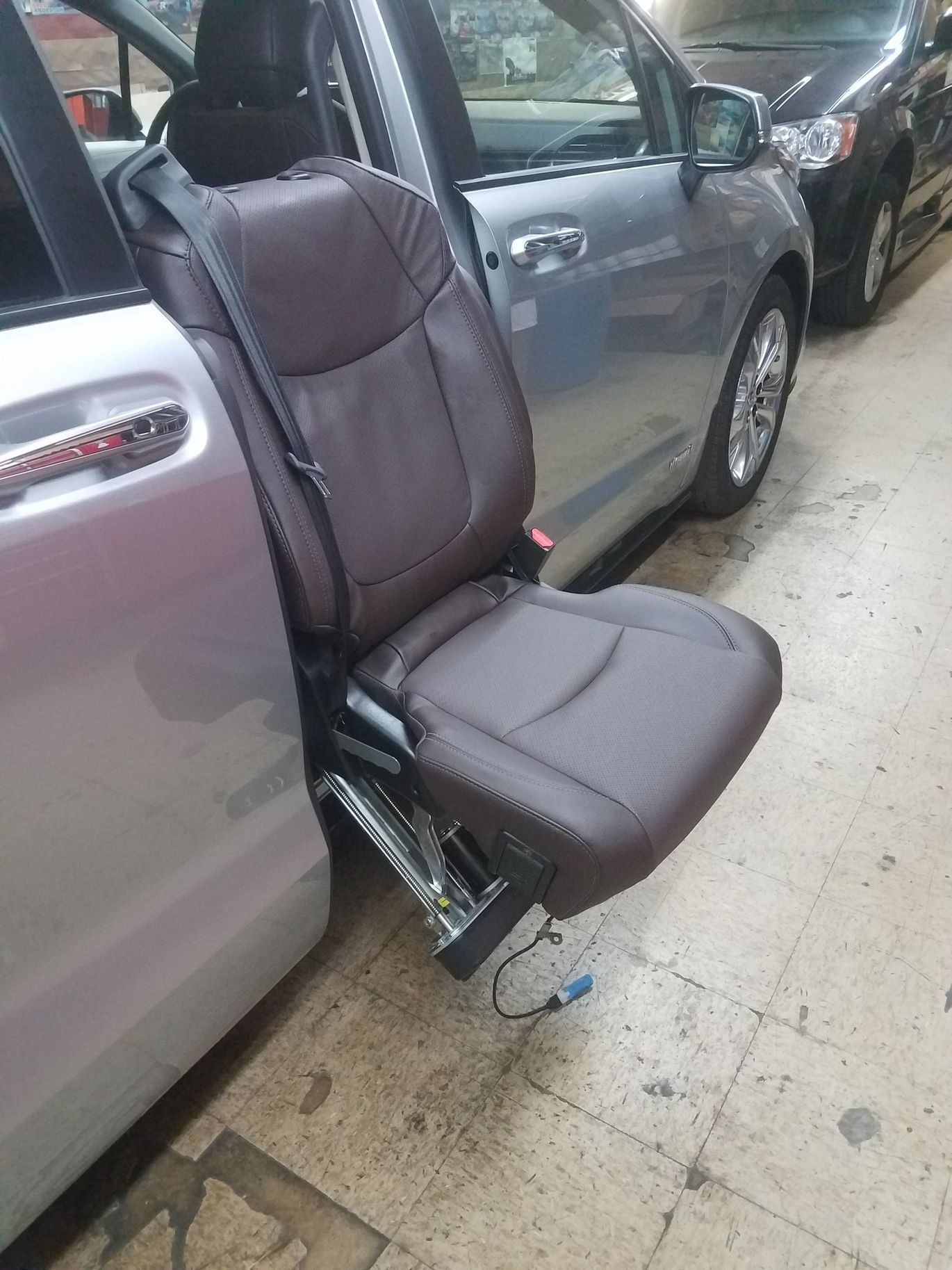 A car seat is sitting in the back of a silver minivan.