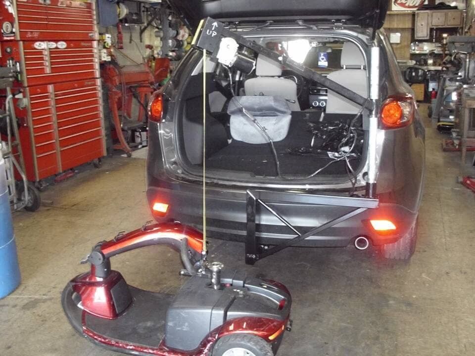 A mobility scooter is attached to the back of a car