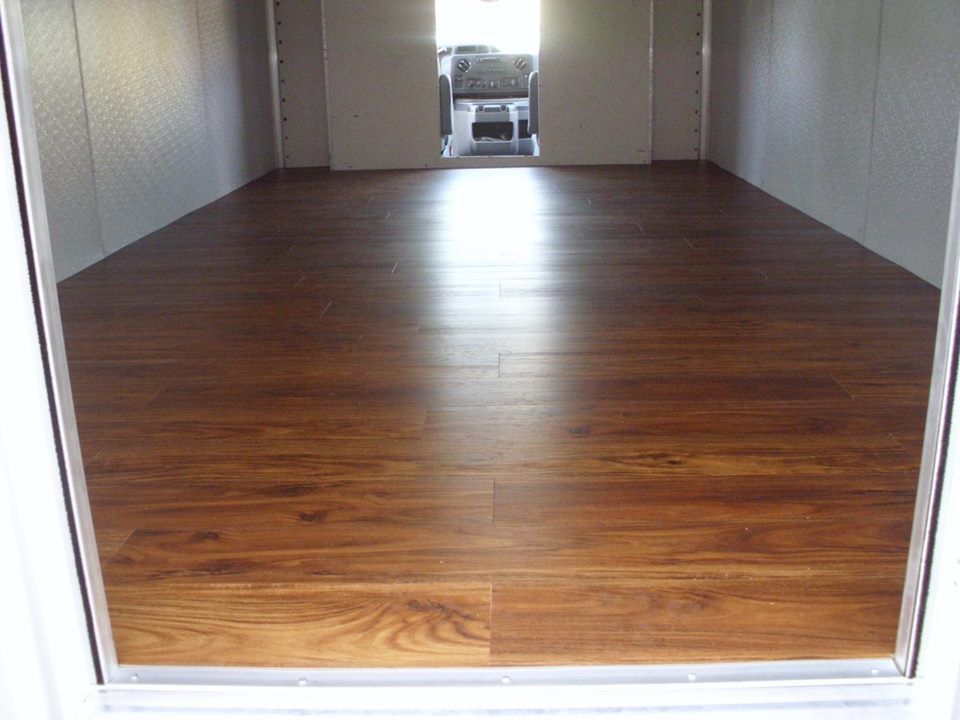 A room with a wooden floor and a car in the background