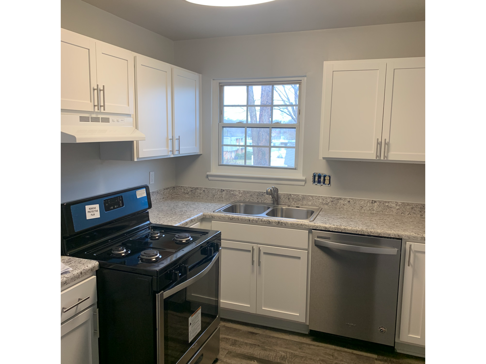 Kitchen with white cabinets, a black gas stove, stainless steel appliances, and a window.