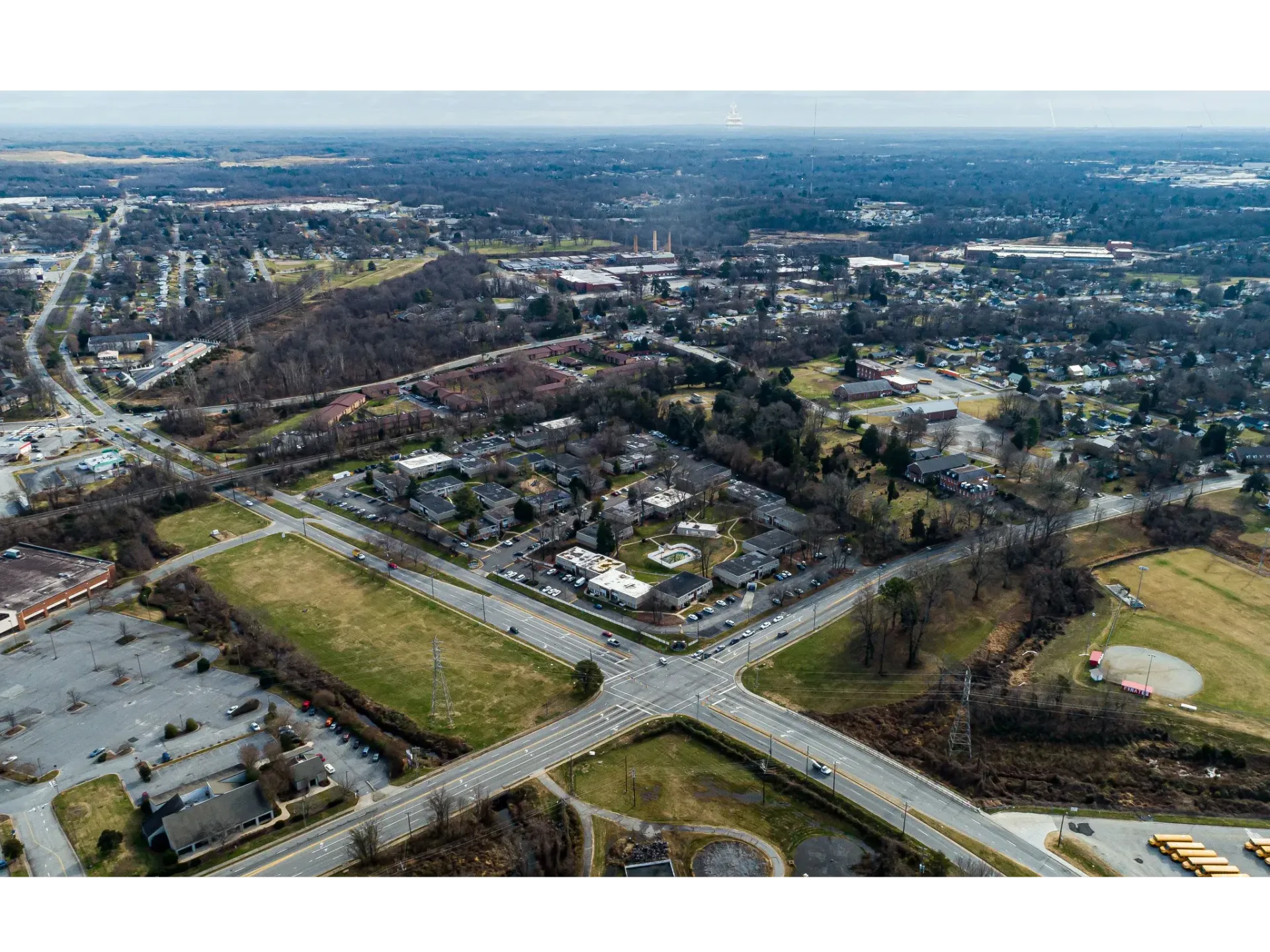 Aerial view of a suburban area with roads, buildings, and open fields.