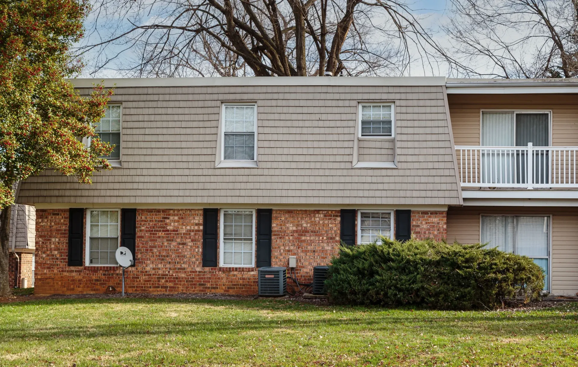 Exterior of a two-story apartment building with brick lower level and beige siding.