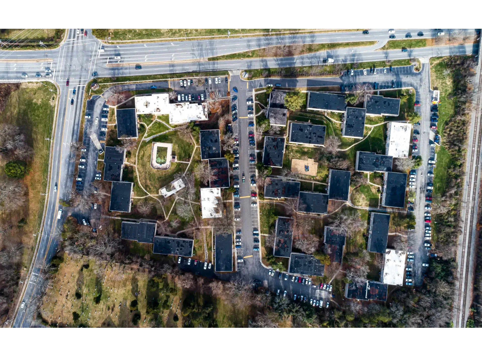 Aerial view of a large apartment complex with interconnected buildings, parking lots, and green courtyards.