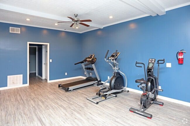 Gym with treadmill, elliptical, and exercise bike; blue walls, beige flooring at New Irving Heights, which offers apartments in Greensboro, NC.