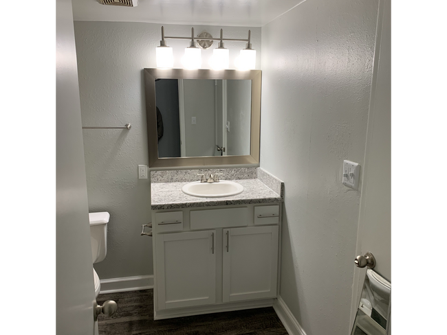 Small bathroom with white vanity, gray countertop, and mirror at New Irving Heights, which offers pet-friendly apartments for rent in Greensboro, NC.