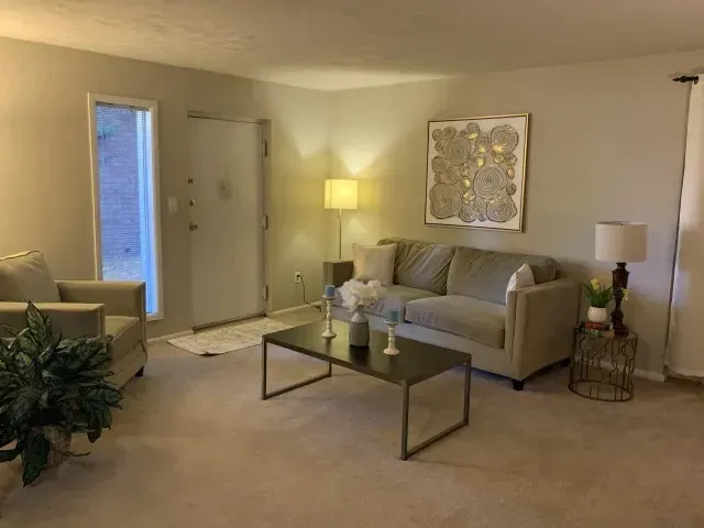 Living room with a beige couch, coffee table, and artwork at New Irving Heights, which offers apartments near downtown Greensboro, NC.