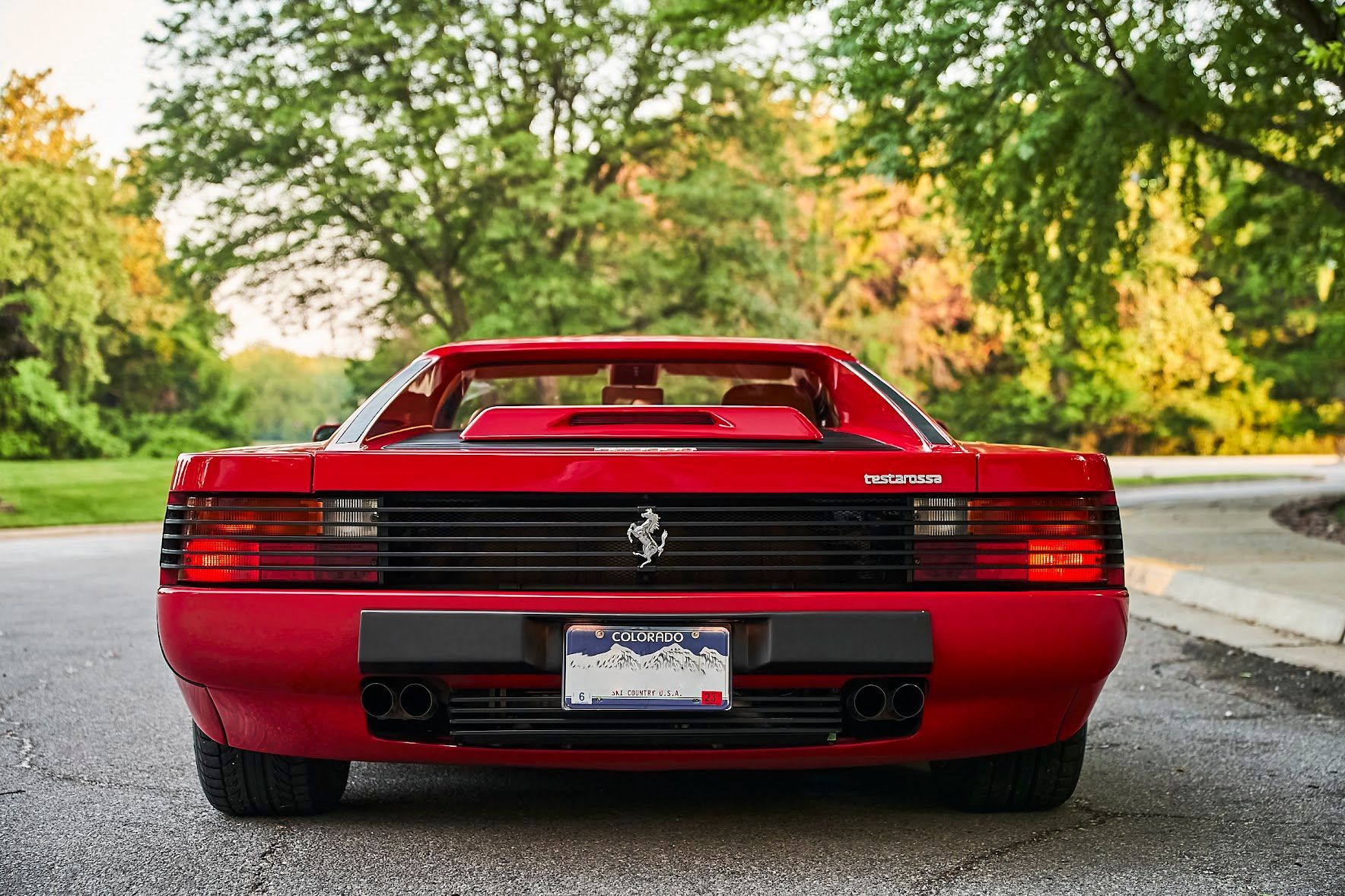 A red ferrari testarossa is parked on the side of the road.