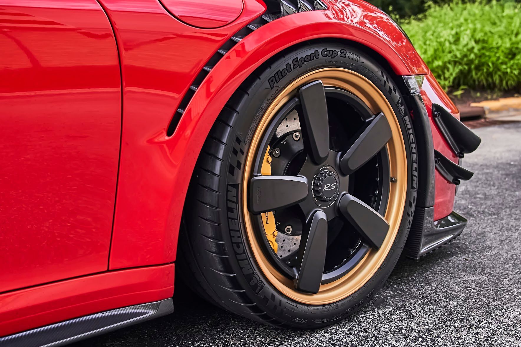 A close up of a red car 's wheel and tire.