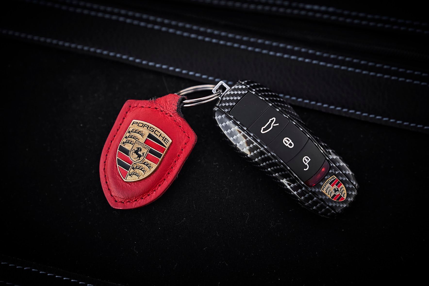 A car key with a porsche logo on it is sitting on a black leather seat.