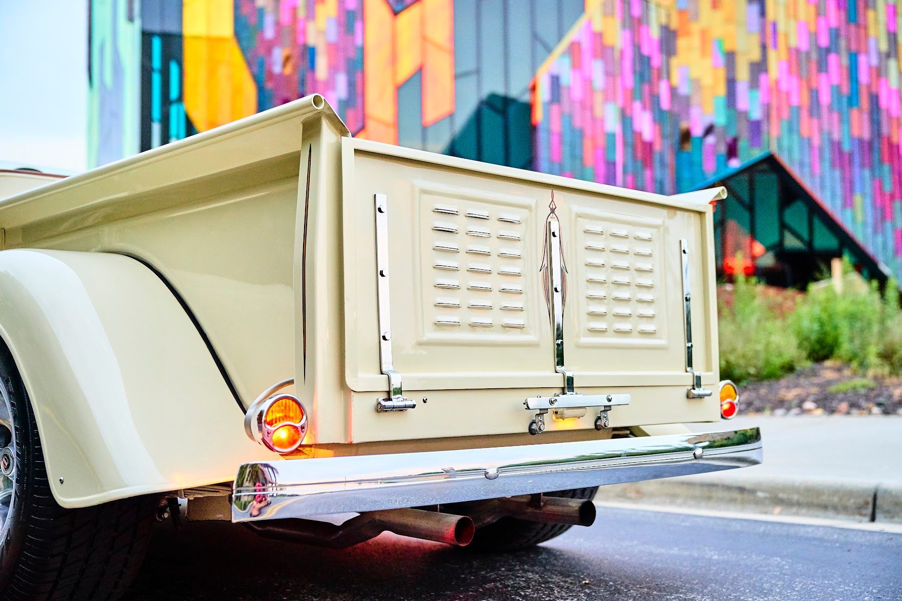 A white truck is parked on the side of the road in front of a colorful building.