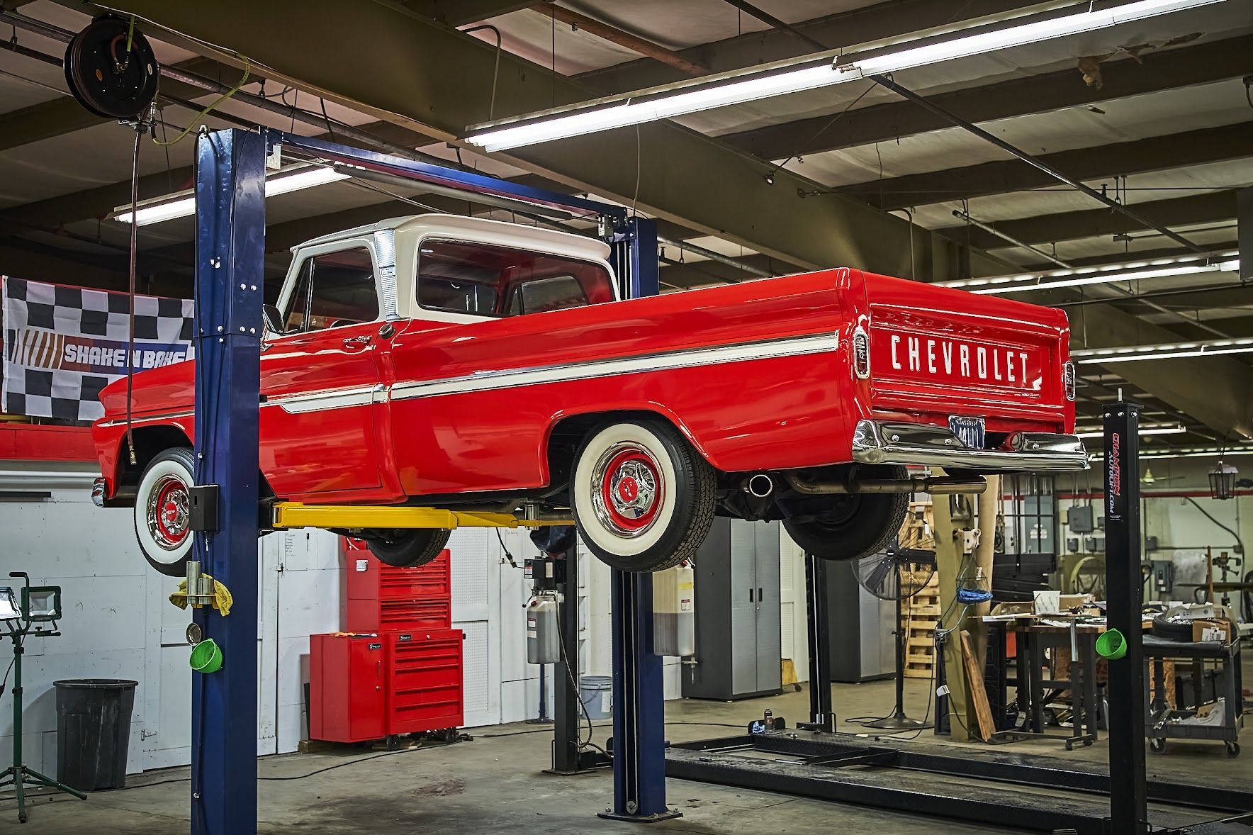 A red truck is sitting on a lift in a garage.