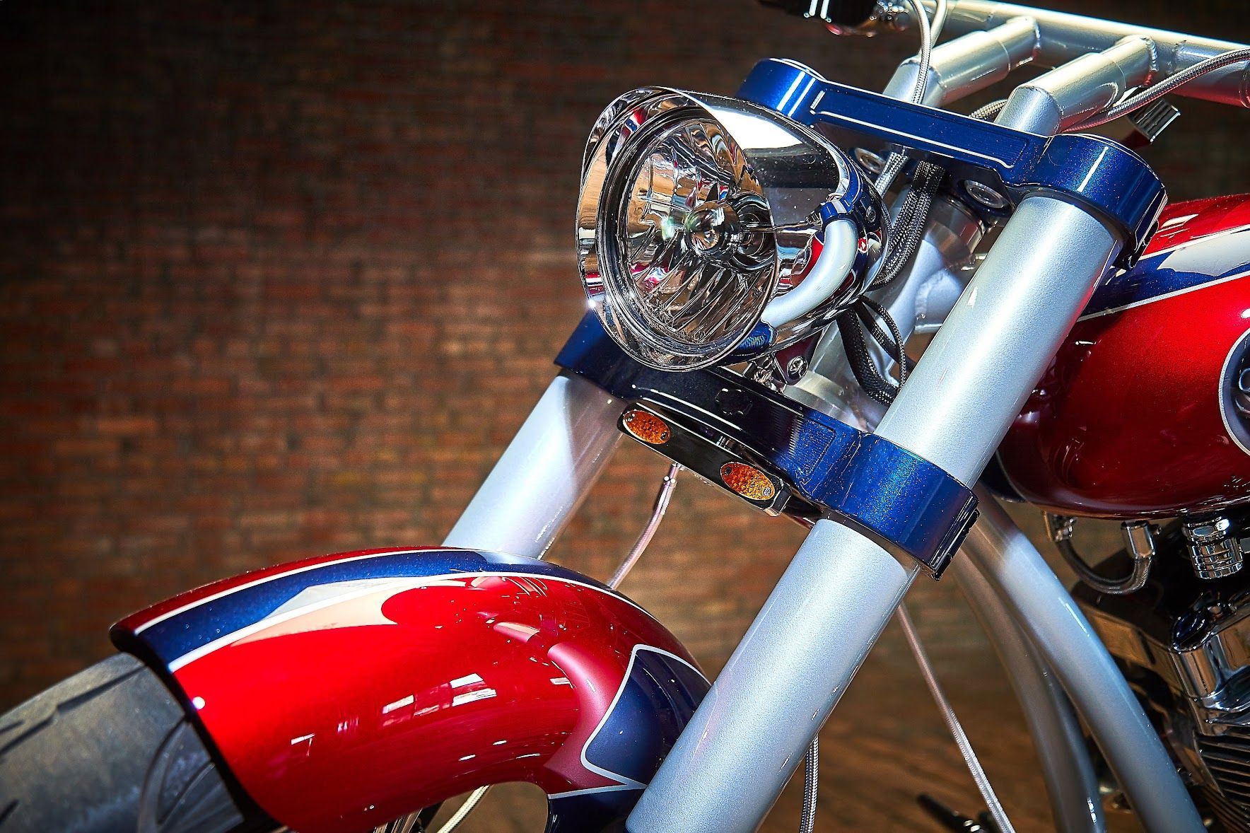 A red white and blue motorcycle is parked in front of a brick wall