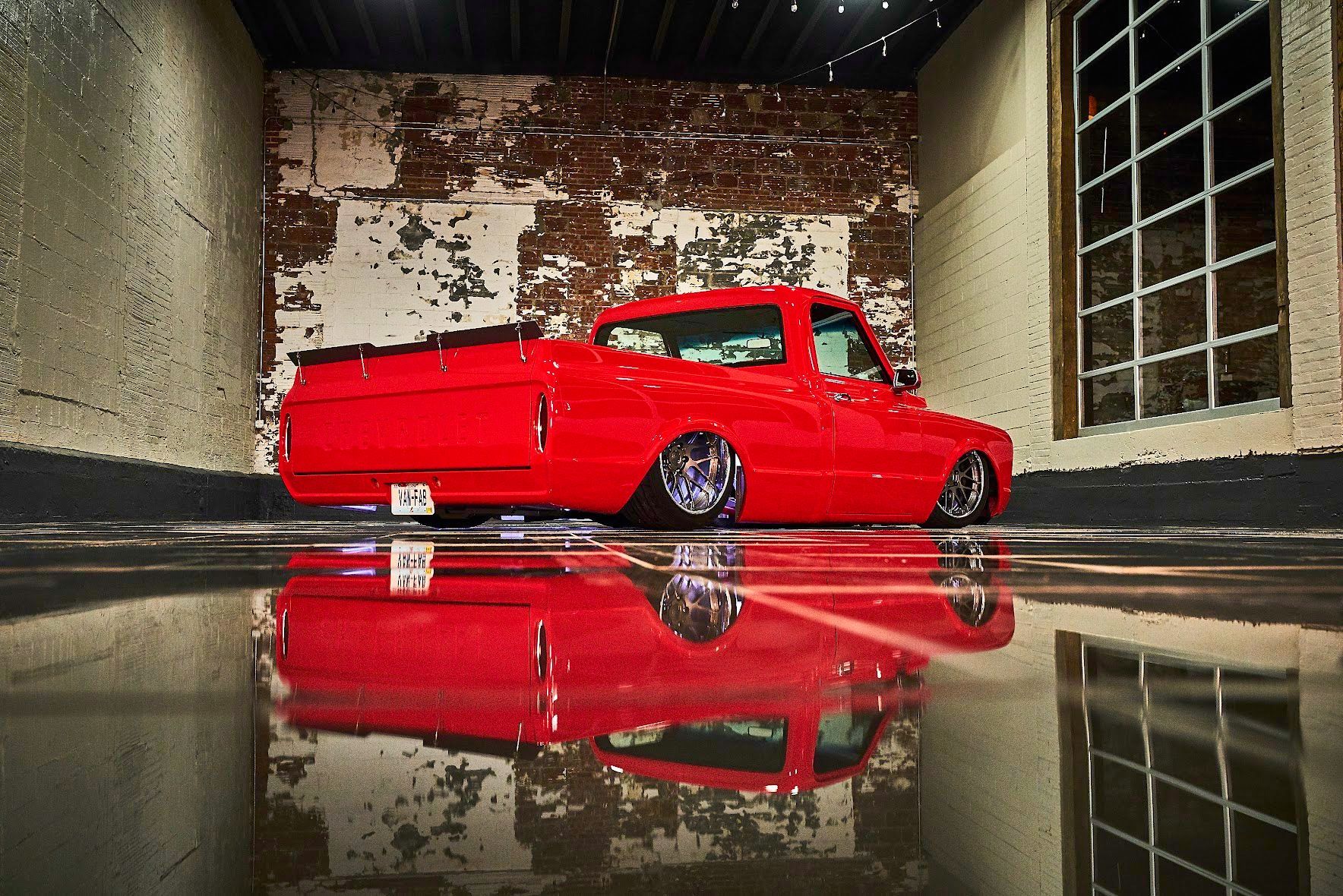 A red truck is parked in a garage next to a brick wall.