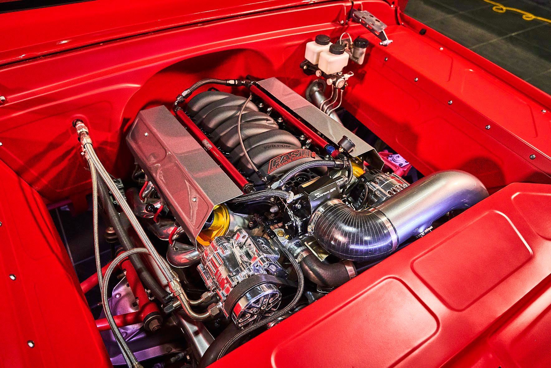 A close up of a red car engine with the hood open
