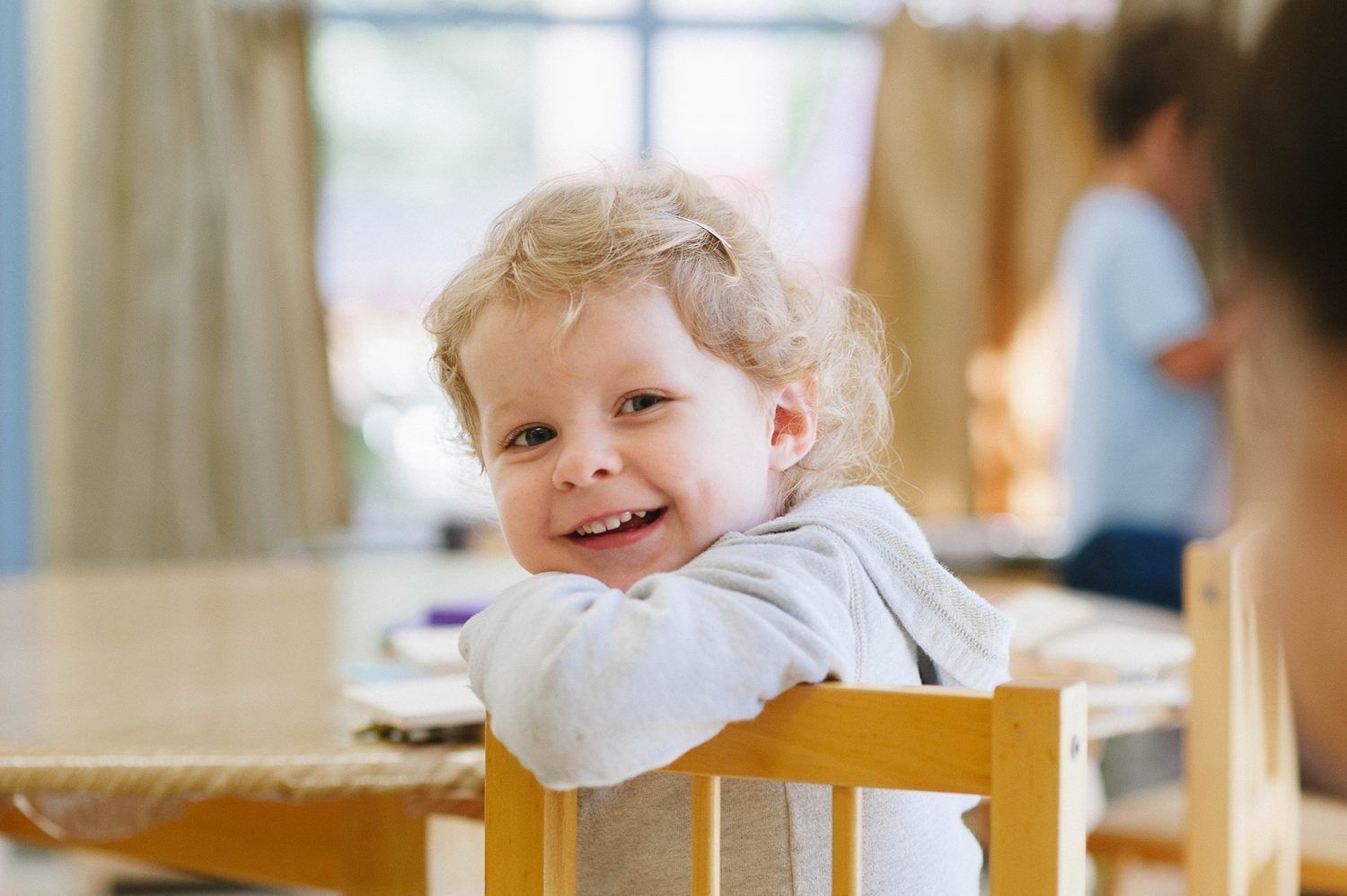 a Montessori child is sitting in a chair and smiling at the camera