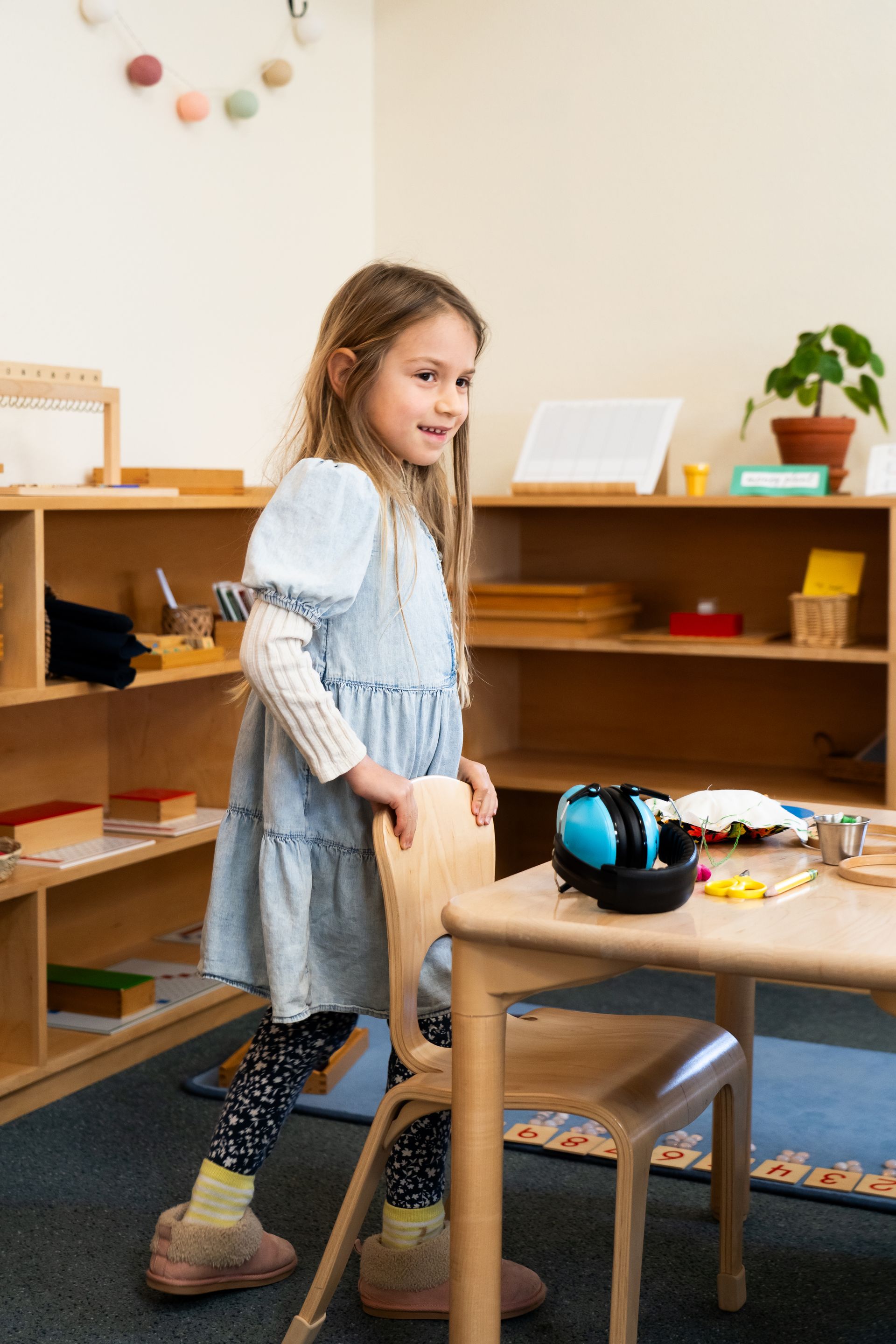 a Montessori child is sitting in a blue chair reading a book