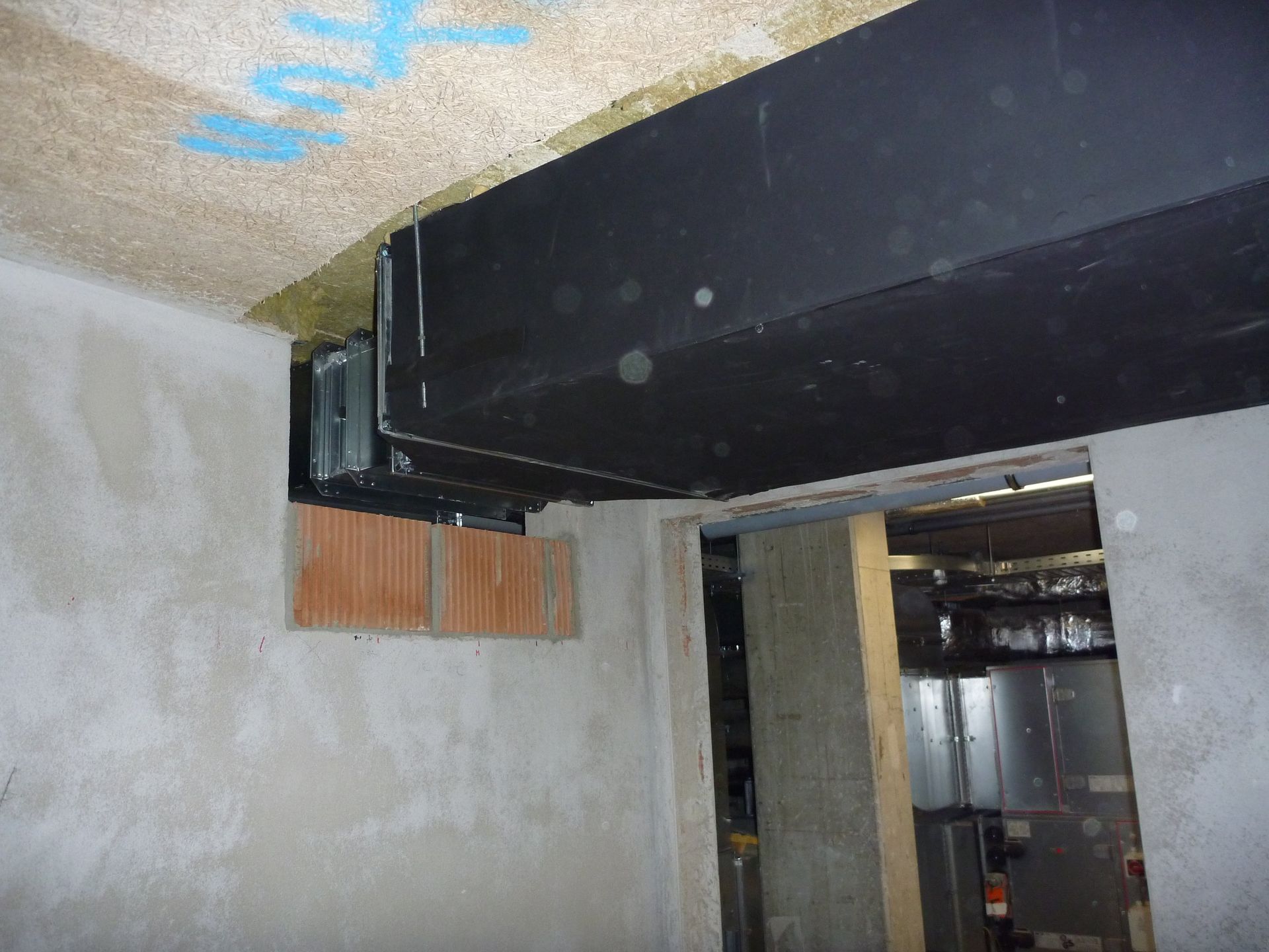In einem Raum hängt ein schwarzer Balken von der Decke