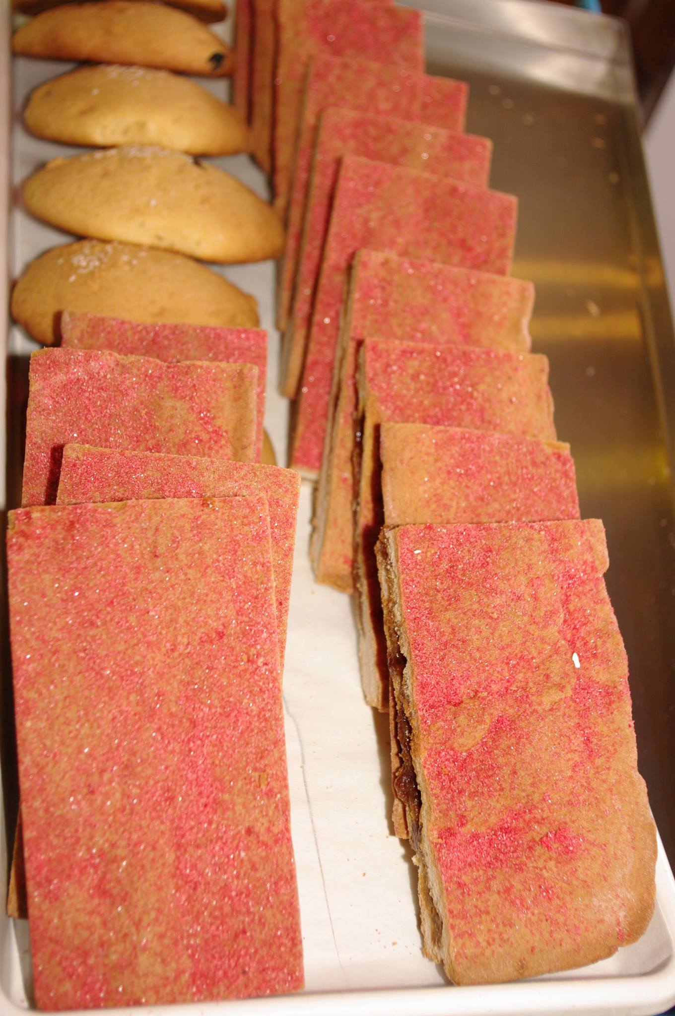 A tray of cookies and slices of cake with red sprinkles