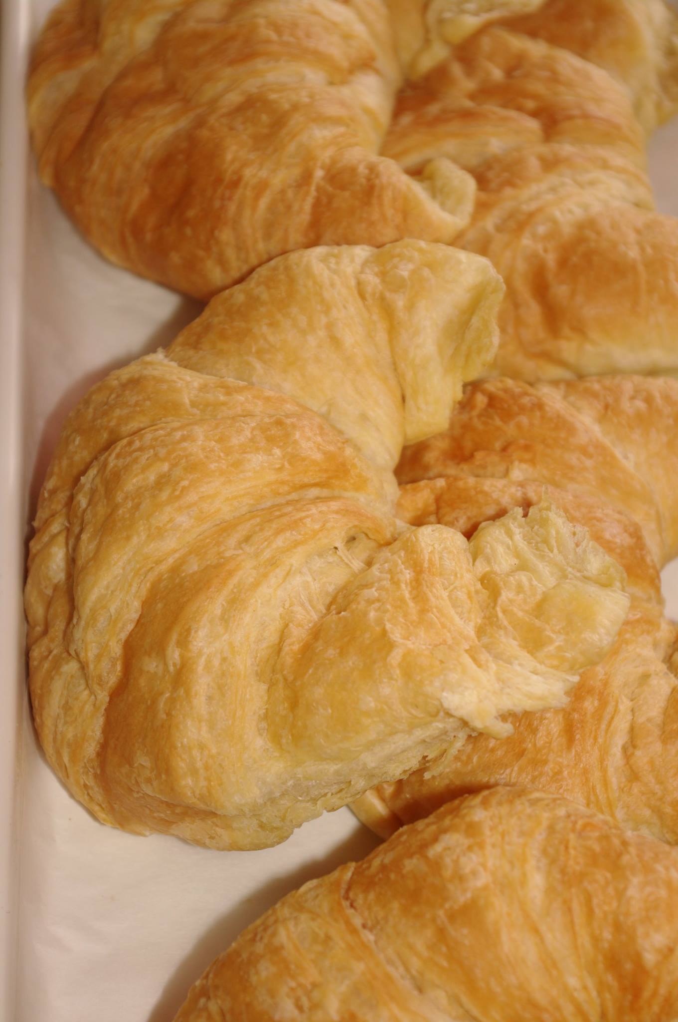 A close up of three croissants on a white tray.