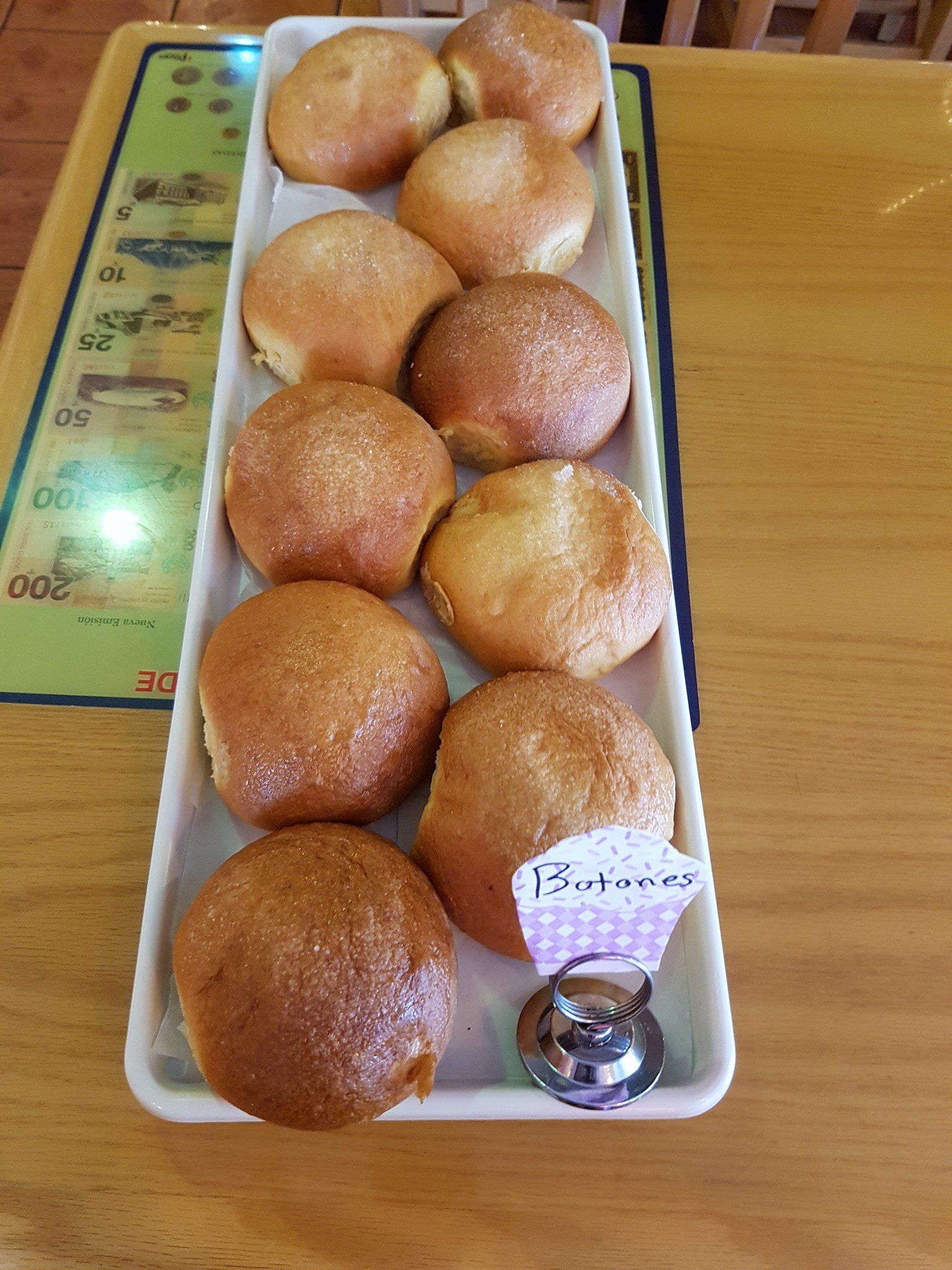 A tray of doughnuts is sitting on a wooden table.