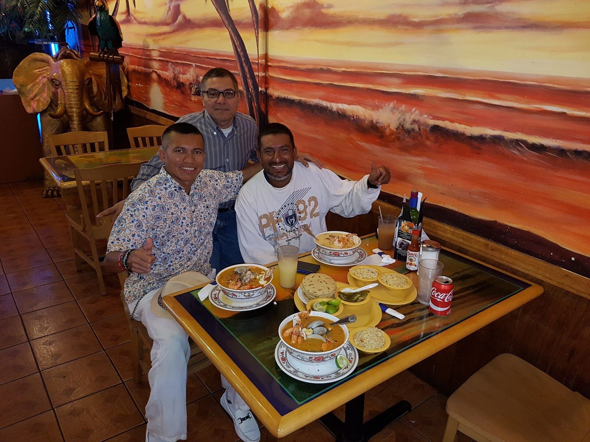 A group of men are sitting at a table with plates of food.