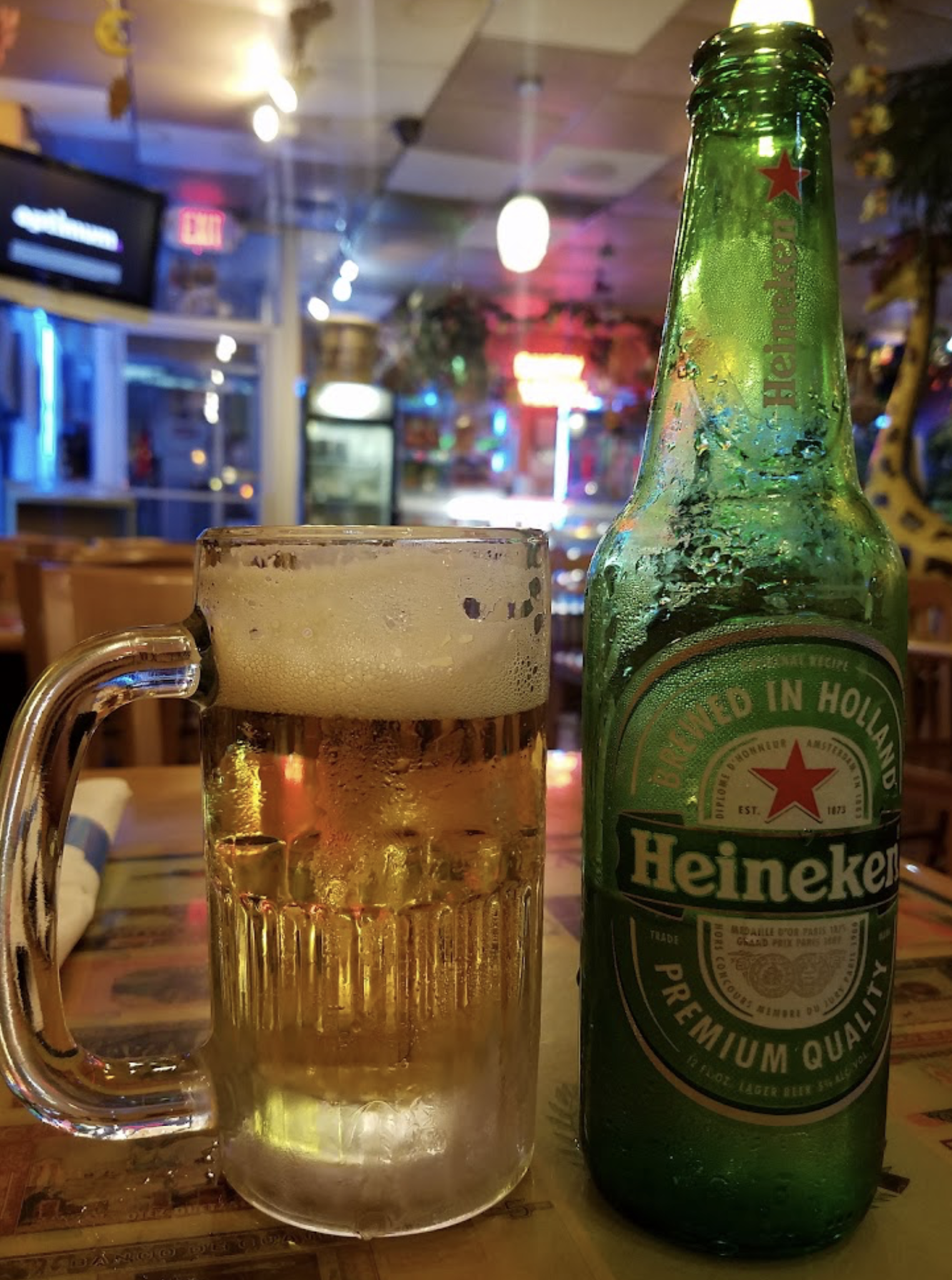 A bottle of heineken beer next to a glass of beer on a table.