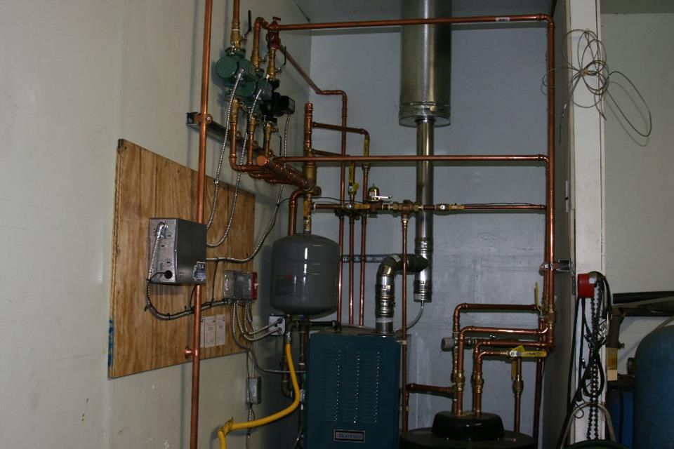 A room filled with lots of pipes and a boiler.