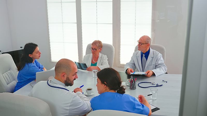 a group of doctors and nurses are having a meeting in a conference room .