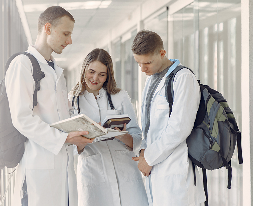 a group of doctors are standing in a hallway looking at a book .