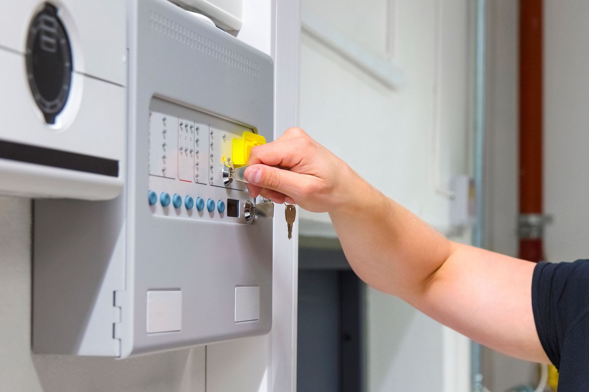 A person is pressing a button on a fire alarm system.