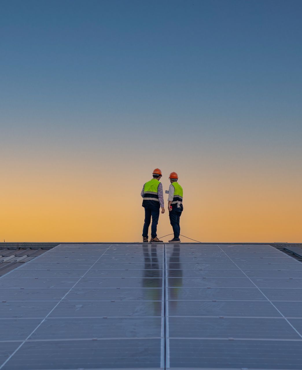 Two men are standing on top of a solar panel.