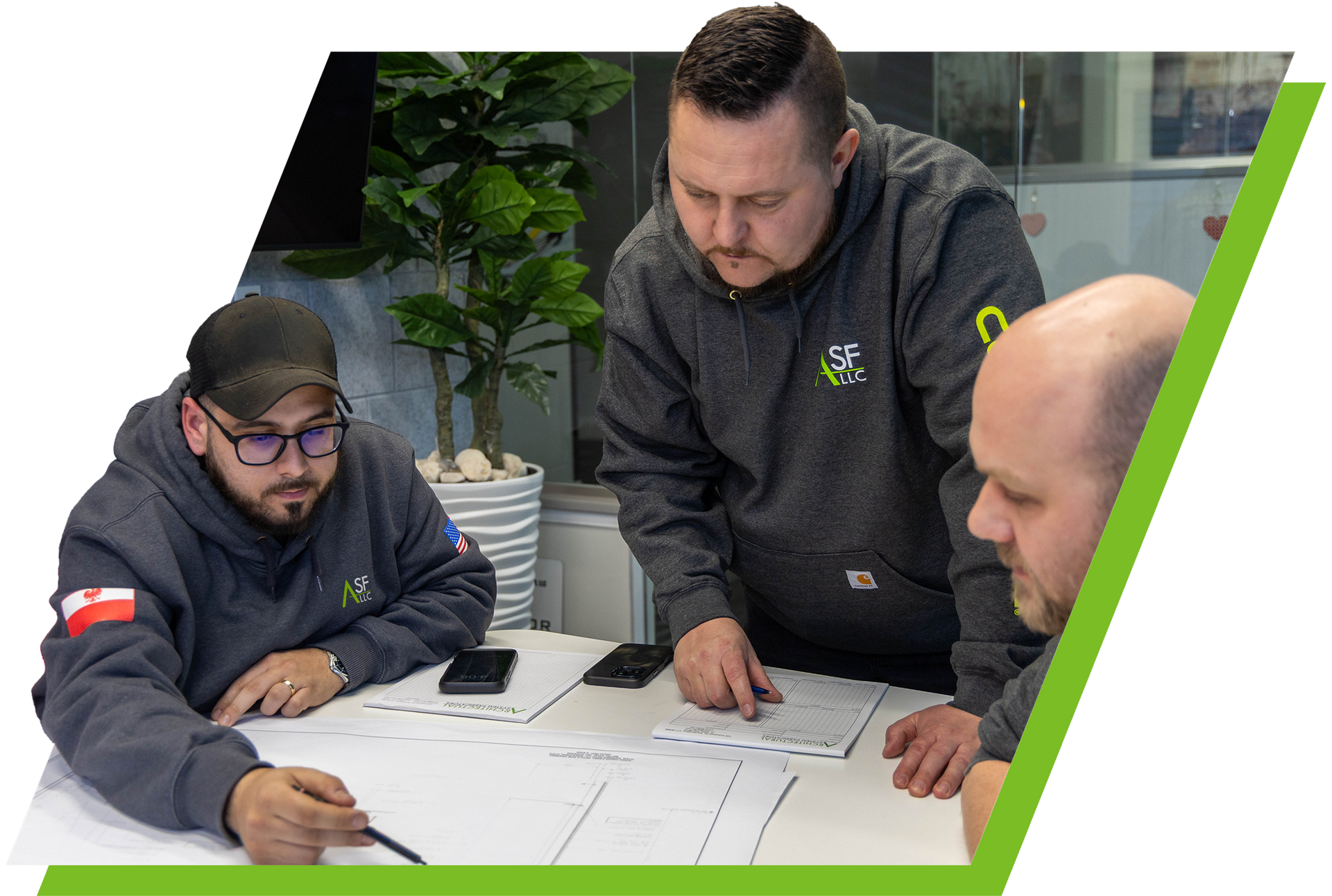 A group of men are sitting around a table looking at a blueprint.