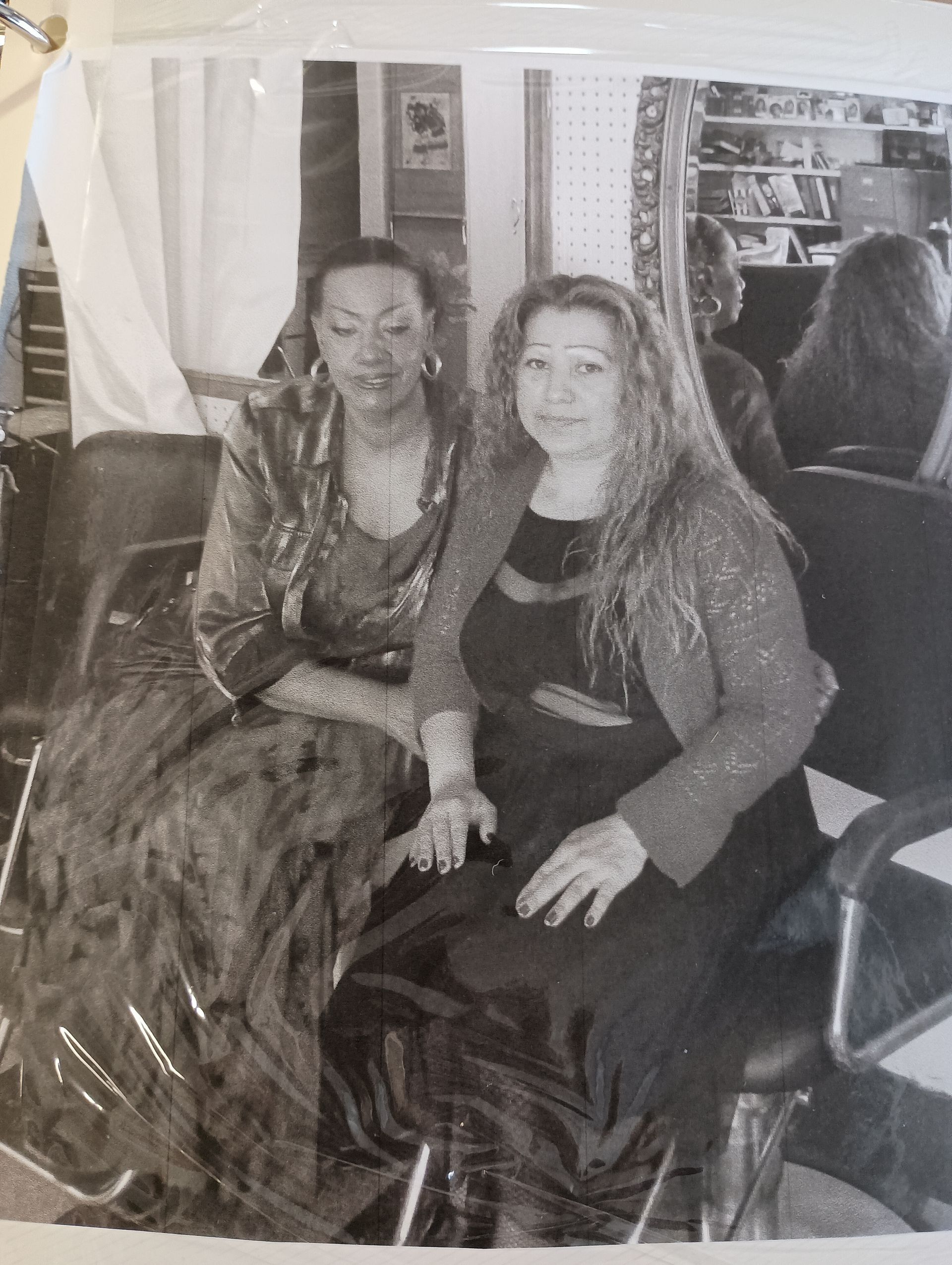 Two women are sitting next to each other in a chair in a black and white photo.