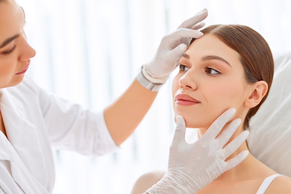 A woman is getting her face examined by a doctor.