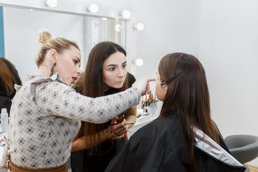 A woman is applying makeup to another woman in a salon.